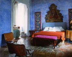 a bed sitting in the middle of a bedroom next to a window with an ornate painting on it