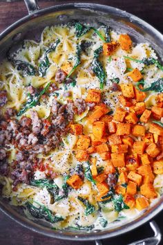 pasta with sausage, spinach and cheese in a pan on a wooden table top