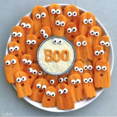 a white plate topped with carrots covered in goo eyes and the word boo spelled out