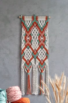 a crocheted wall hanging on the wall next to some yarn and a plant