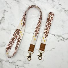 two lanyards with brown and white leaves on them sitting on a marble surface