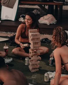 two women and one man are playing with blocks on the floor while others sit around