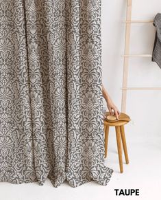 a person standing in front of a curtain with the word taupe written on it