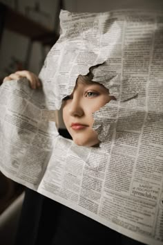 a woman holding up a newspaper with her face through the hole in it's paper