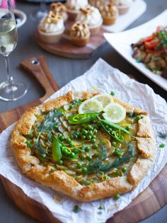 a pizza with asparagus, peas and lemon wedges