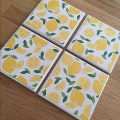 four coasters with lemons on them sitting on top of a wooden table next to each other