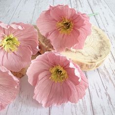 pink flowers are sitting on a piece of wood