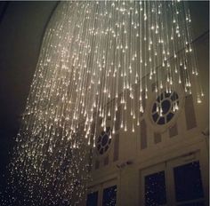 a chandelier hanging from the ceiling in front of a building with lights on it