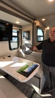 a man standing next to a table in a living room on a motorhome