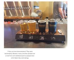 a wooden tray with four different types of beers on it and a man standing in the background