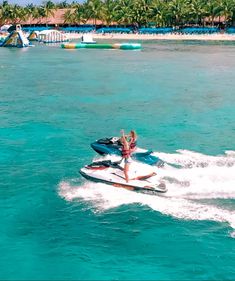 a person on a jet ski in the water with palm trees and blue skies behind them