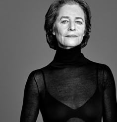 an older woman wearing a black turtle neck top with sheer fabric on her body and hands behind her back