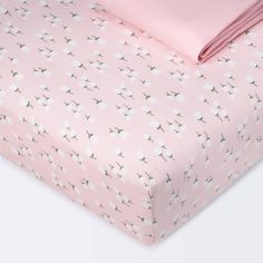 a pink bed sheet with white flowers on it and two matching pillow cases next to each other