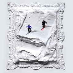 two skiers are skiing down a snow covered slope in an ornate frame on the wall