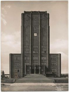 an old black and white photo of a tall building with stairs leading up to it