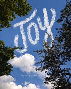 the word you spelled out in the sky above some trees with clouds and blue sky