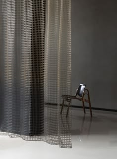 a chair sitting in front of a sheer curtain