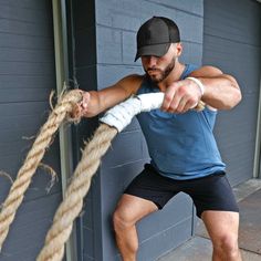 a man is holding on to a rope with his hands while standing in front of a building