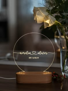 a glass vase with white flowers and a personalized acrylic sign on it