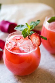 two glasses filled with watermelon and mint garnish on top of a table