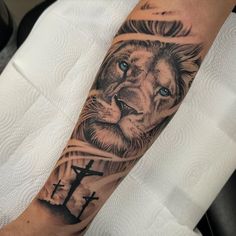 a man with a lion tattoo on his arm and cross in the foreground next to him