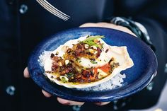 a person holding a blue plate with food on it