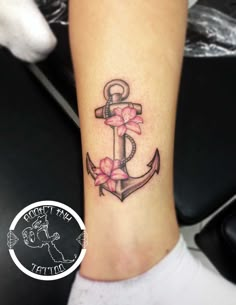 a small anchor with pink flowers on the side of her leg and an inscription that says,