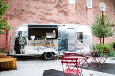 an ice cream truck parked in front of a building with tables and chairs around it