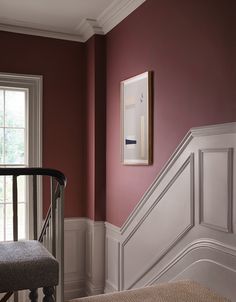 a room with red walls and white trim on the wall, along with a gray bench