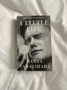 a book about a man's life is laying on a white bed sheet with the cover pulled back