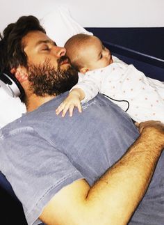 a man laying in bed holding a baby