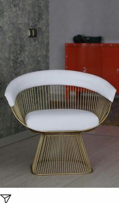 a white and gold chair sitting on top of a wooden floor next to a red cabinet