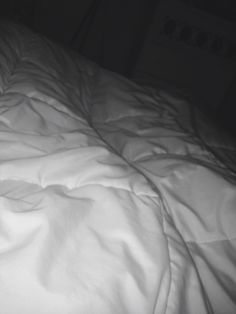 an unmade bed with white sheets and pillows