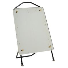 a white sign sitting on top of a metal stand with two black legs and one white board attached to it