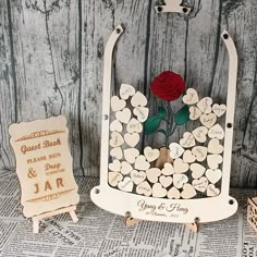 a wooden card holder with a red rose on it and two small cards in front of it