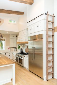 a kitchen with an oven, refrigerator and stairs leading to the second floor above it