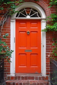 an orange front door on a brick building