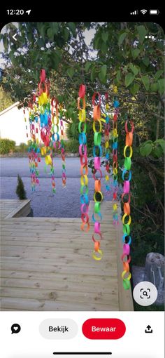 colorful streamers hanging from the side of a wooden deck in front of a tree