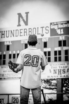 black and white photograph of a baseball player in front of the thunderbirds stadium sign