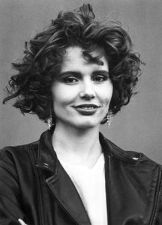 black and white photograph of a woman with curly hair wearing a leather jacket smiling at the camera