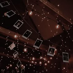 several polaroid frames are hung on a string with fairy lights strung from the ceiling