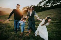 a family holding hands and walking through a field at sunset with the sun setting behind them