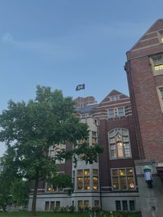 an old brick building with a flag flying in the wind on a clear blue day