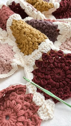 crocheted flowers are arranged on a white tablecloth with green needles in the middle