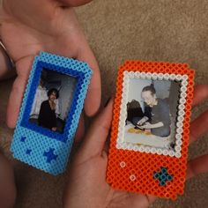 two people are holding small legos in their hands, one has an orange and blue frame