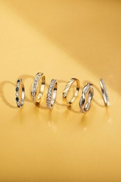 five different types of rings sitting on top of a yellow surface with the word love spelled in cursive writing