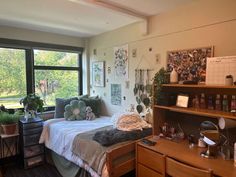 a bed room with a neatly made bed and lots of plants on the windowsill