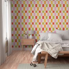 a bed sitting in a bedroom next to a wall with different colored squares on it