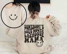 a woman wearing a sweatshirt with the words somebody's loud mouth volleyball mama printed on it