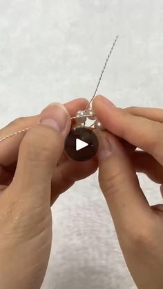 two hands are working on an ornament that looks like a bead ball